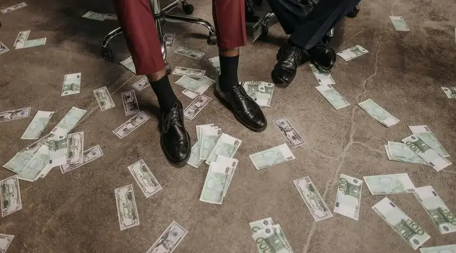 Two people in an office with euro banknotes scattered on the floor, showcasing a financial theme.