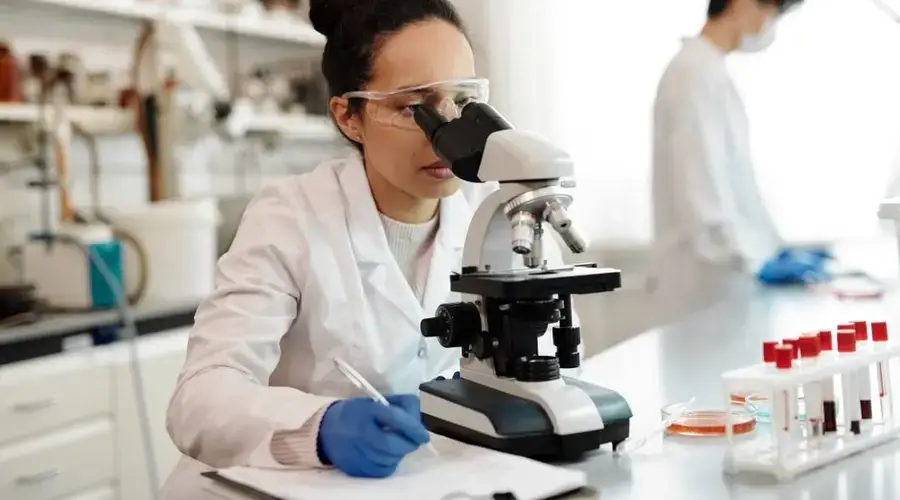 A scientist in a lab coat using a microscope in a modern laboratory setting.
