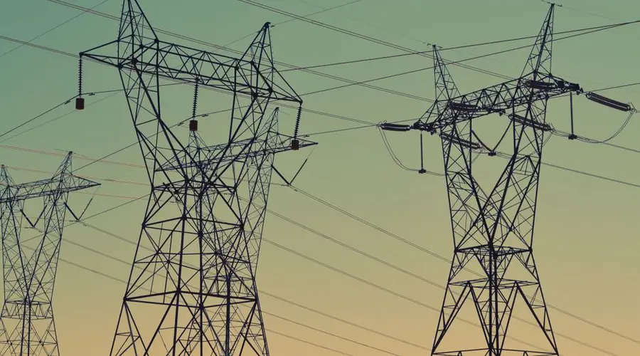 Silhouette of high voltage power lines against a twilight sky, illustrating energy infrastructure.