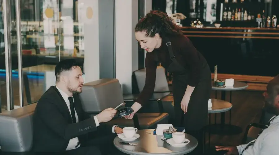 Business professionals in a café, paying with a card. Modern ambiance.