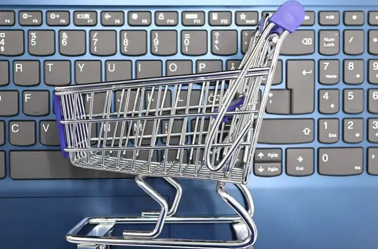 A miniature shopping cart placed on a laptop keyboard symbolizing online shopping and e-commerce.