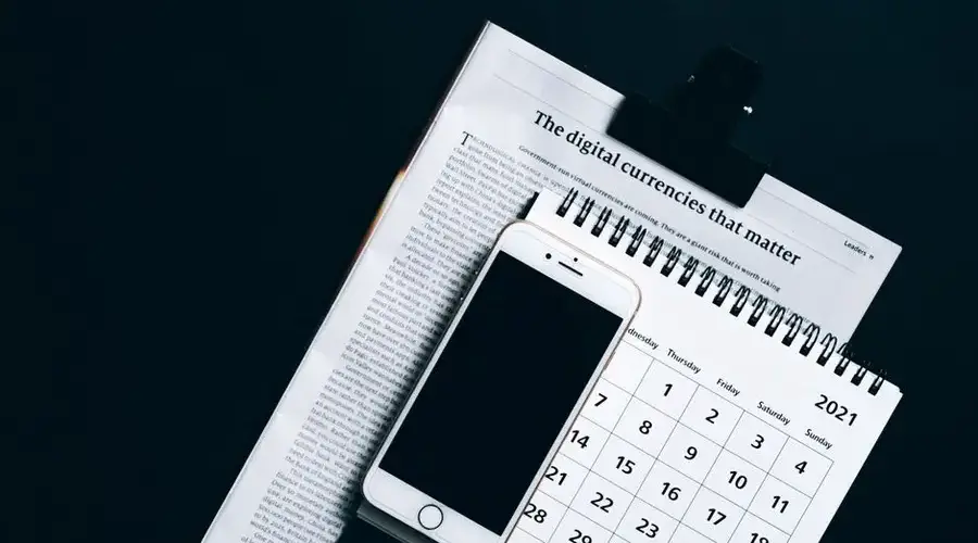 A smartphone placed on a newspaper and calendar, symbolizing modern digital finance.