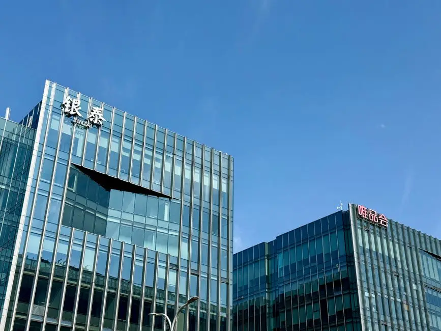 Close-up of modern glass facade buildings under a clear blue sky in Shanghai, China.