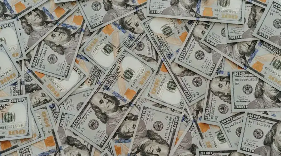 US hundred dollar bills scattered in abundance creating a financial backdrop.