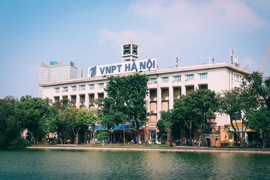 Scenic view of the VNPT building in Hanoi with lush greenery and water reflections.