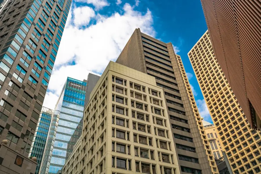 Low angle view of diverse skyscrapers in Hong Kong under a bright sky.