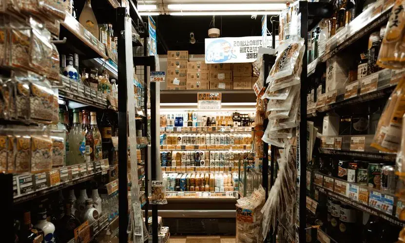 Explore a bustling Tokyo convenience store aisle packed with diverse products and merchandise.