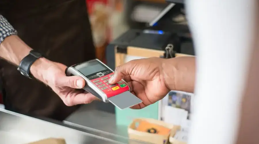 A customer uses a card for a contactless payment at a retail store. Business and consumerism concept.
