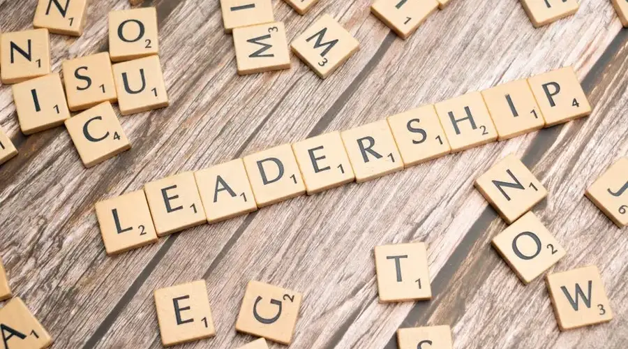 Wooden letter tiles spelling 'LEADERSHIP' on a wooden surface, symbolizing leadership qualities and skills.