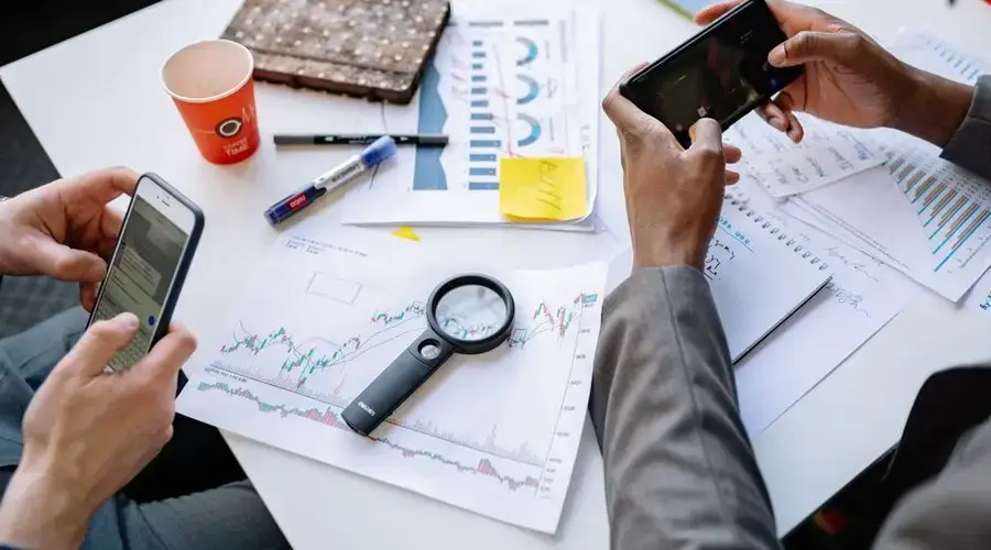 Two professionals analyzing data and graphs with smartphones on a white table.