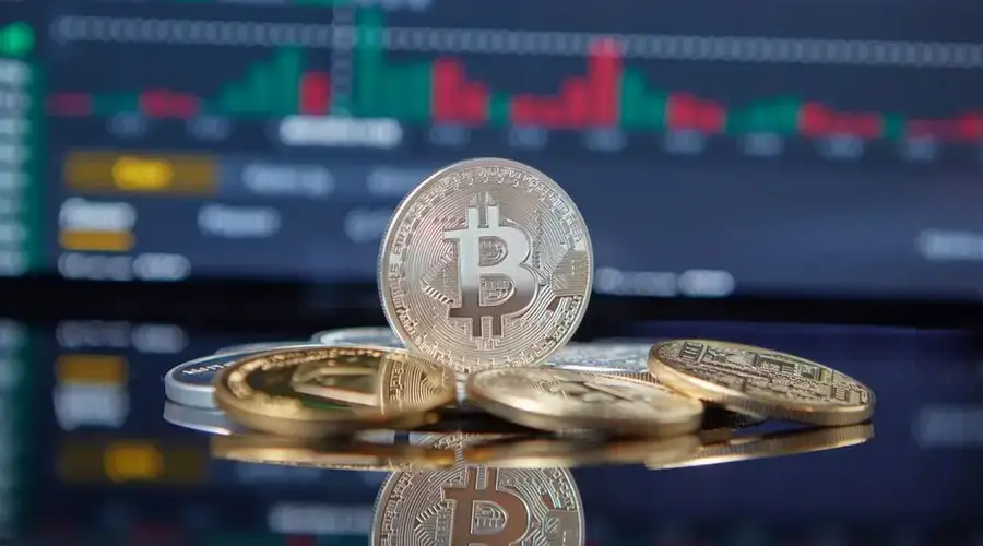 Bitcoin cryptocurrency coins in focus with a blurred stock market chart in the background, representing investment and finance.