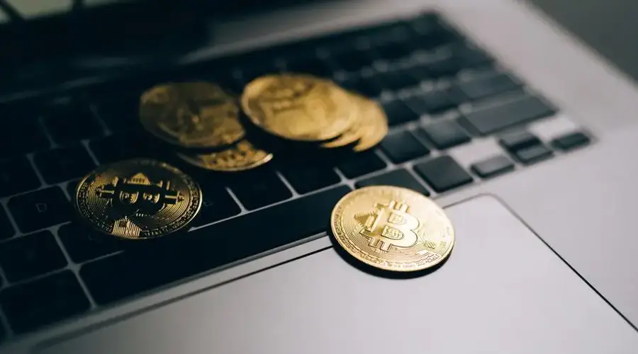 Close-up of golden Bitcoins placed on a laptop keyboard, symbolizing digital currency and modern finance.