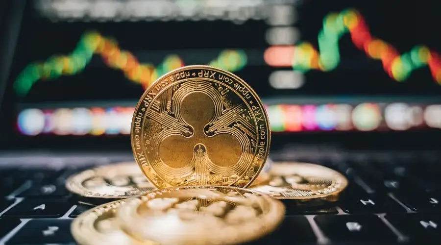 Golden Ripple XRP coins on laptop, symbolizing cryptocurrency trends and online trading.