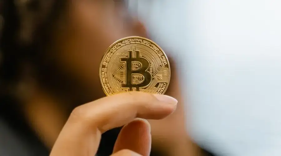 A hand holding a Bitcoin coin, representing cryptocurrency and blockchain technology investment.