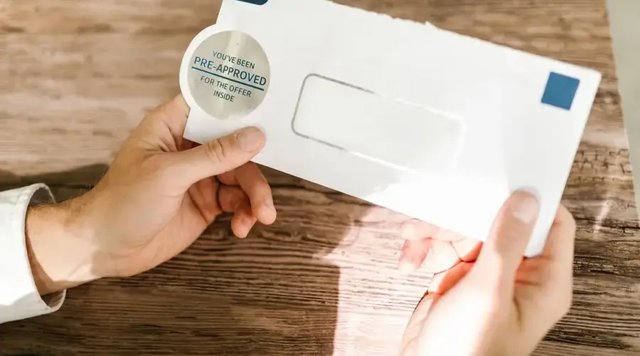 Hands holding a pre-approved offer envelope on a wooden table. Perfect for financial marketing.