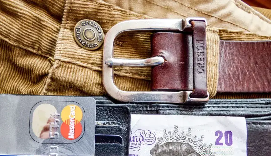 A detailed image of a wallet containing credit cards, a leather belt, and currency, emphasizing personal finance.