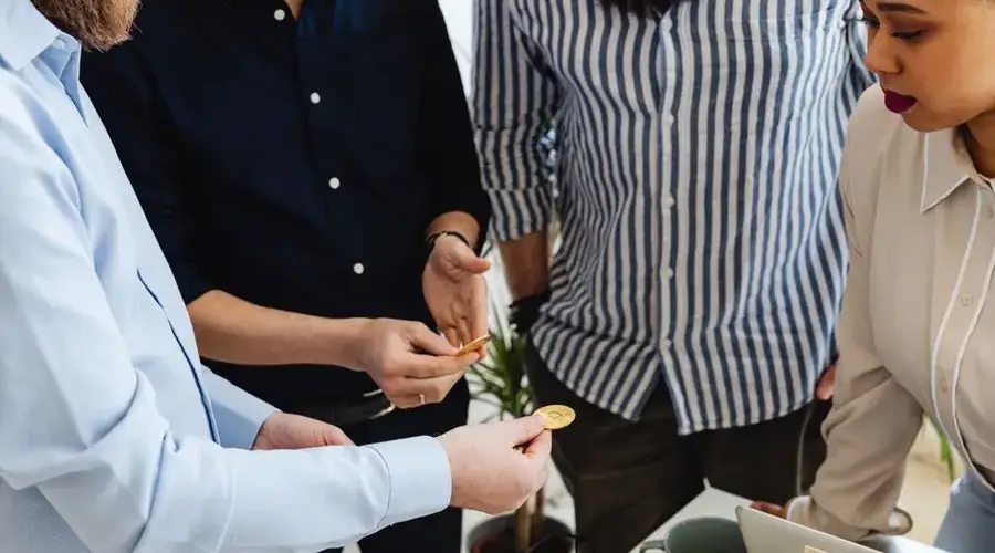 Business colleagues working with Bitcoin during a meeting, exchanging ideas in office setting.