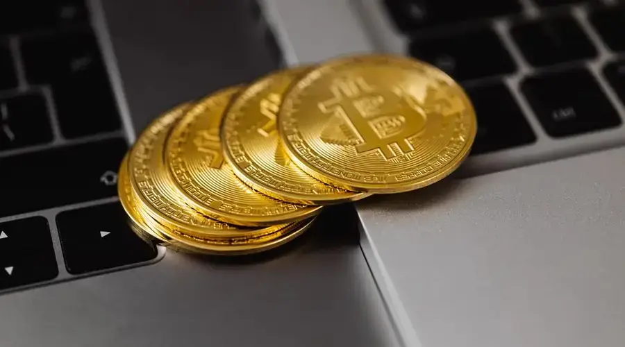 Close-up of golden bitcoins on a laptop keyboard representing digital currency and wealth.