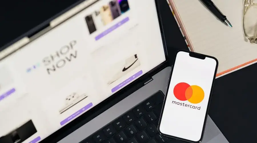 Laptop and smartphone with Mastercard logo, illustrating online shopping and digital payments.