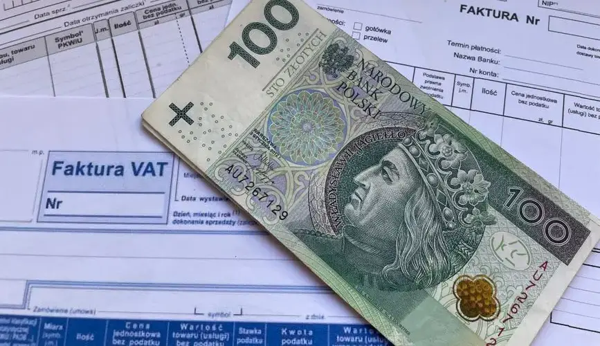 A 100 Polish Zloty note placed on top of business VAT invoices, symbolizing finance and economics.