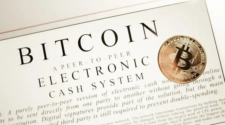 Image depicting Bitcoin electronic cash system with a physical Bitcoin coin prominently displayed.