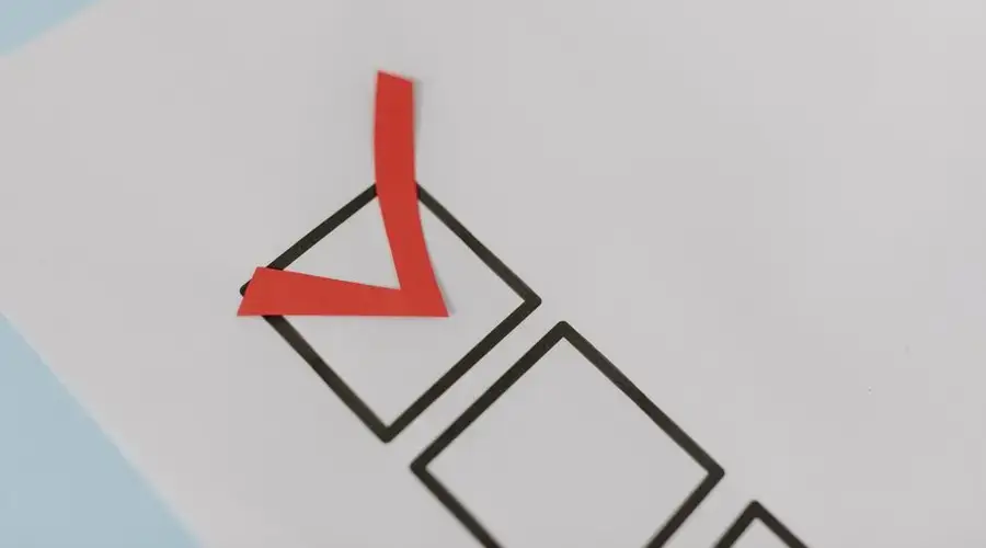 Close-up of a red check mark on a crisp white paper with black boxes, symbolizing completion.