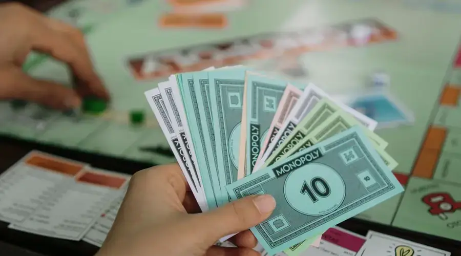 A close-up view of a person holding Monopoly money while playing the board game.