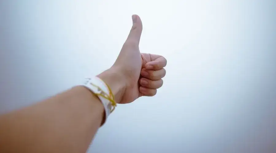 A hand giving a thumbs up gesture symbolizes approval and positivity.
