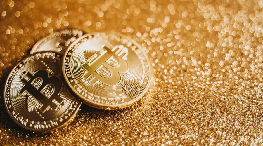 Close-up of Bitcoin coins on a sparkling gold glitter backdrop, symbolizing digital wealth.