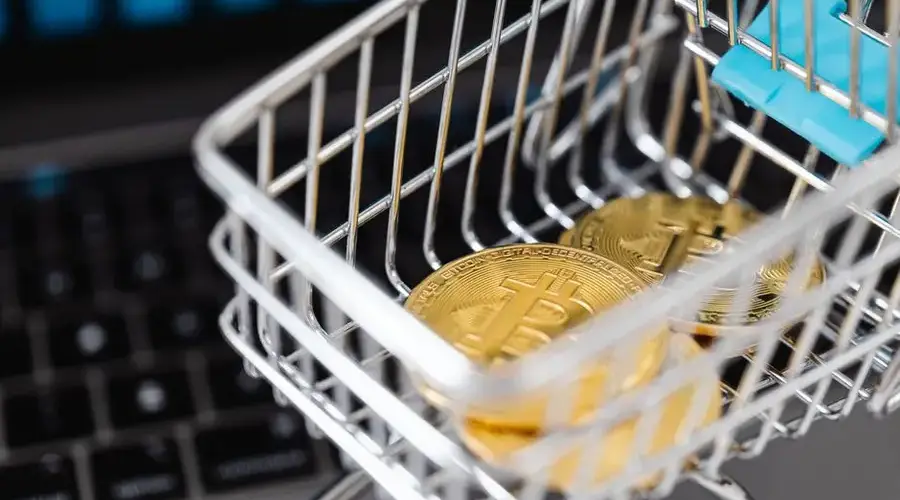 Close-up of bitcoins in a shopping cart placed on a laptop, symbolizing digital currency trading.