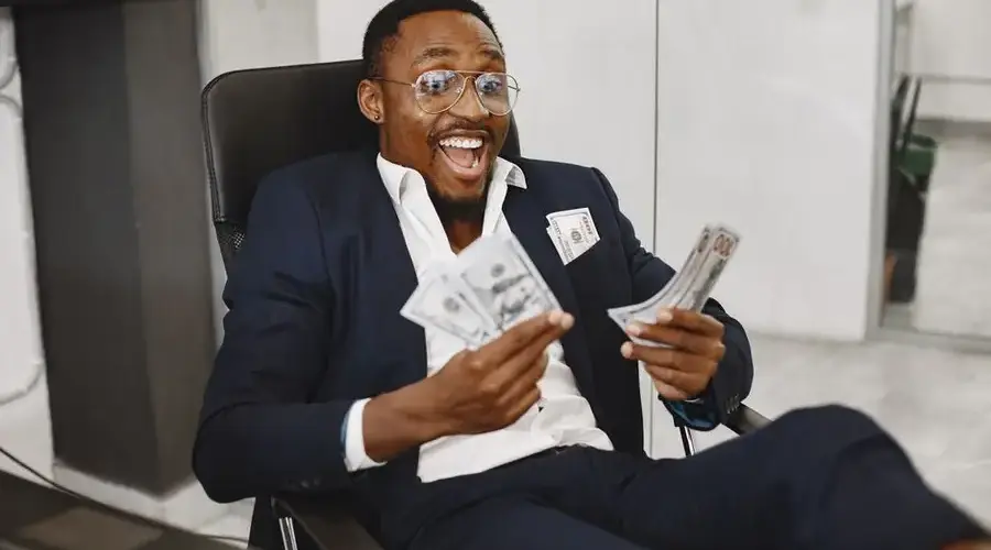 Joyful businessman in suit holding dollar bills, symbolizing success and financial achievement.