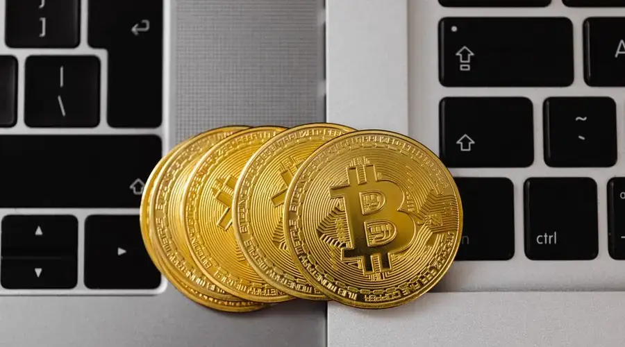 Close-up of Bitcoin coins resting on two laptop keyboards, representing digital currency and technology.