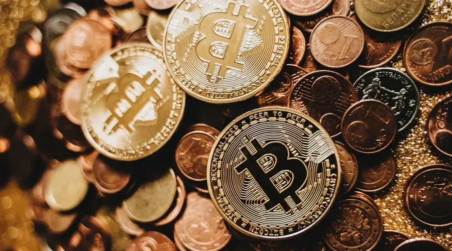 A detailed close-up of shiny bitcoins and assorted coins symbolizing digital currency and wealth.