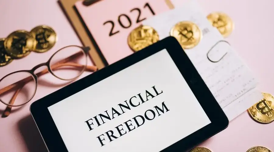 Tablet displaying 'Financial Freedom' surrounded by bitcoins and 2021 planner, symbolizing cryptocurrency potential.