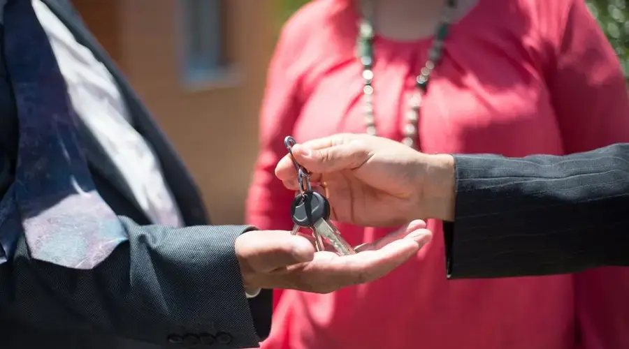Close-up of two people exchanging keys, symbolizing real estate transaction.