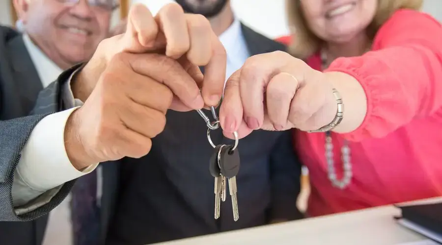 Business colleagues celebrating a successful deal with a handshake and keys exchange.