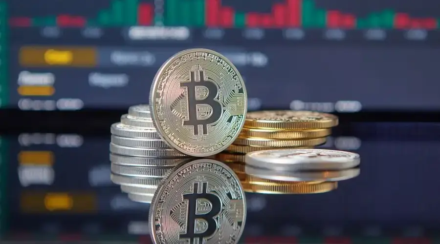 Close-up of Bitcoin coins on reflective surface with financial trading chart, symbolizing cryptocurrency market dynamics.