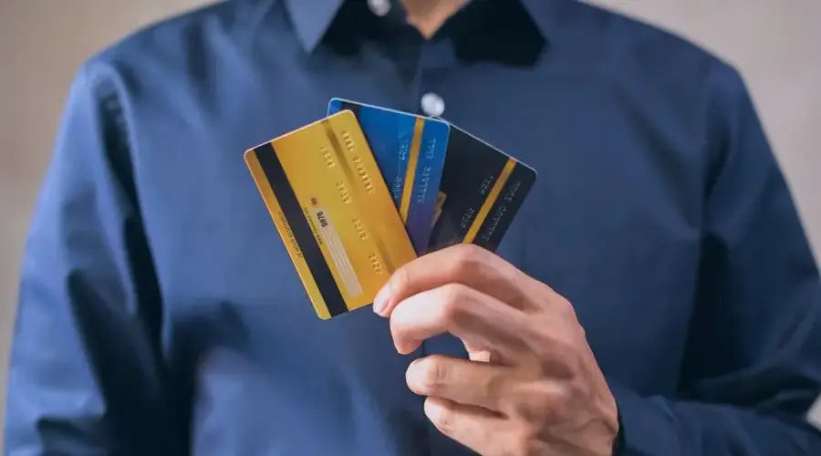 Person holding three credit cards, symbolizing finance, security, and e-commerce.