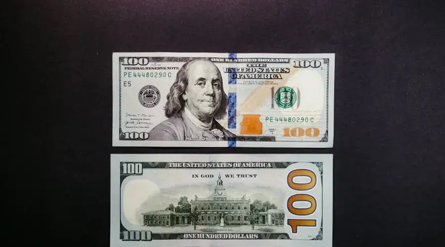 Detailed photo of US hundred dollar bills showing Benjamin Franklin and US currency design.