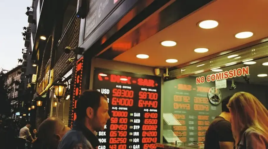 People gathering at a currency exchange office on a busy city street during dusk.