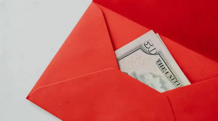 Close-up of fifty dollar bill in a vibrant red envelope, ideal for gift or money exchange stock photo.