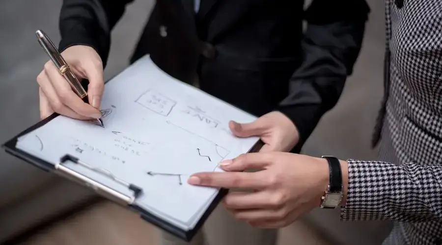 Close-up of professionals collaborating, taking notes on a clipboard.