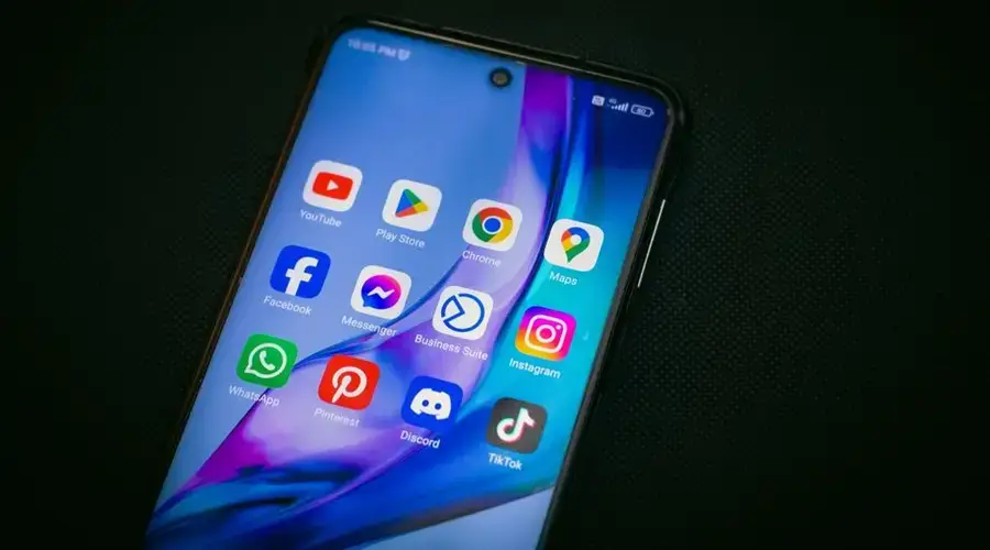 Close-up of a smartphone screen showing popular app icons like YouTube, Maps, and TikTok on a black background.