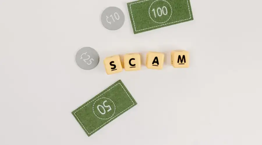 Flat lay of fake currency and scam letters on a gray surface representing financial deception.