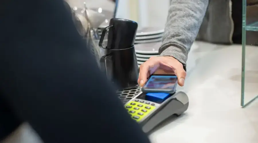 A customer makes a contactless payment using a smartphone at a café, showcasing modern digital transactions.
