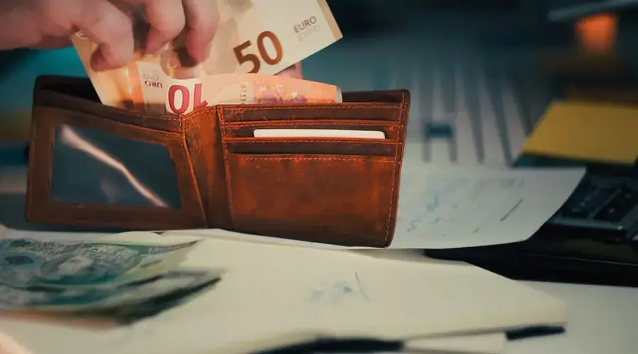 A wallet with euro banknotes and documents on an office desk, symbolizing finance and budgeting.