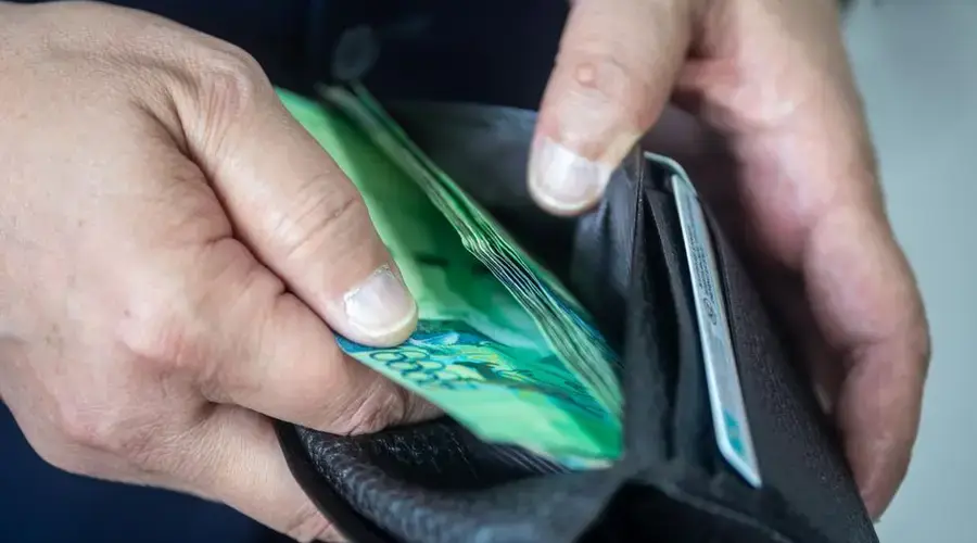 Close-up view of a person holding a wallet with currency. Ideal for financial or economic themes.