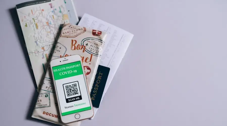 A health passport for COVID-19 displayed on a smartphone alongside travel documents.