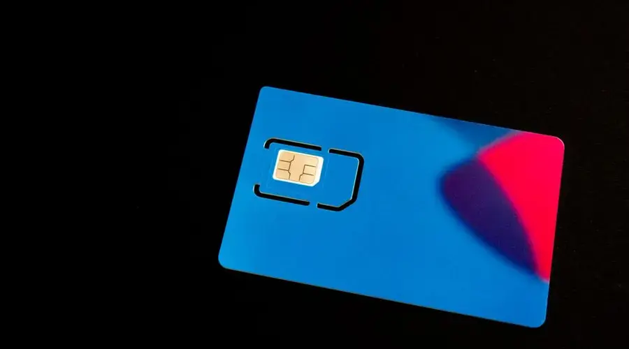 A blue SIM card on a dark background with vibrant red and purple accents.