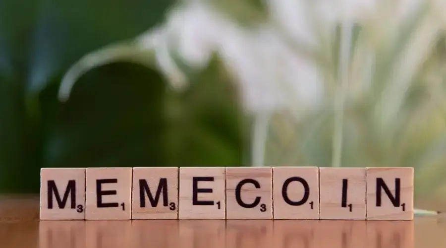 Wooden tiles spelling 'Memecoin' on a blurred background.